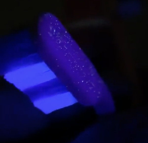 toothbrush under a black light showing particles